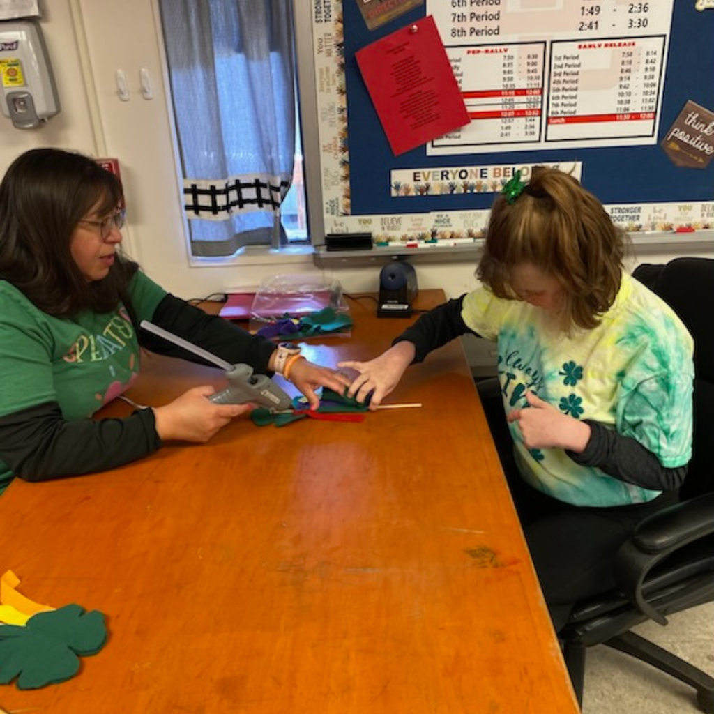 teacher helping glue on streamers with student