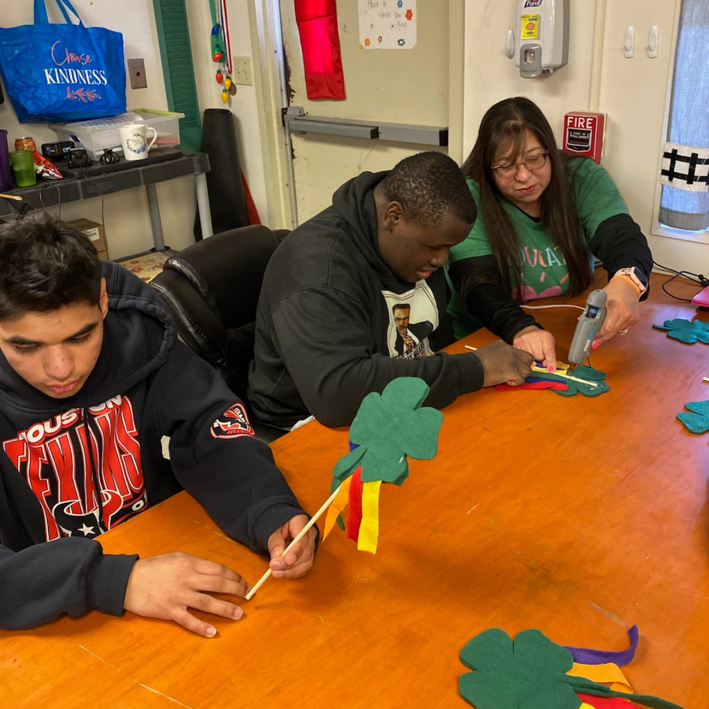 teacher helping glue on streamers with student