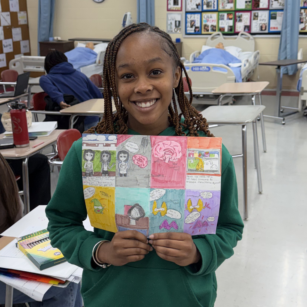 Close-up of a student holding a creative "Super Gland" comic book project, featuring vibrant illustrations of endocrine system-inspired superheroes.