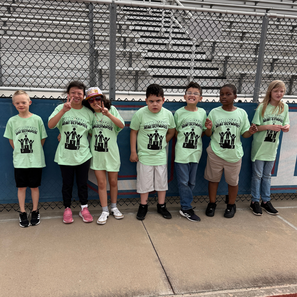 group shot of 7 4th and 5th graders standing by the fence at the track.