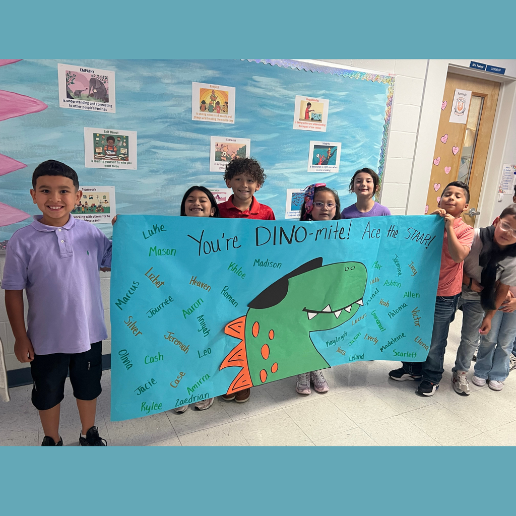 A group of smiling elementary students holding a large, blue handmade poster that says "You're DINO-mite! Ace the STAAR!" The poster features a large green dinosaur head and is covered in student names