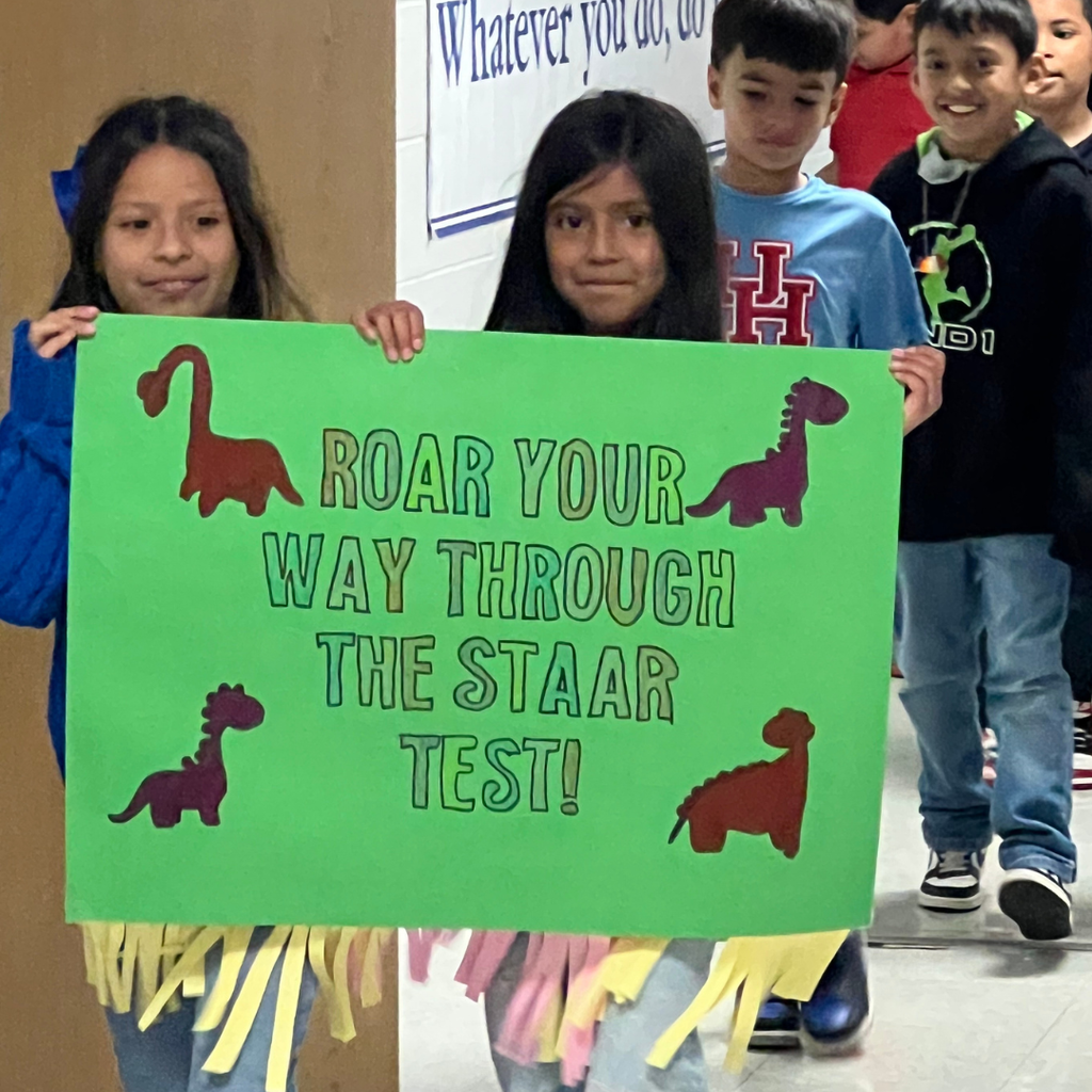 Students holding a green "Roar Your Way Through the STAAR Test!" poster with dinosaur cutouts and colorful streamers.