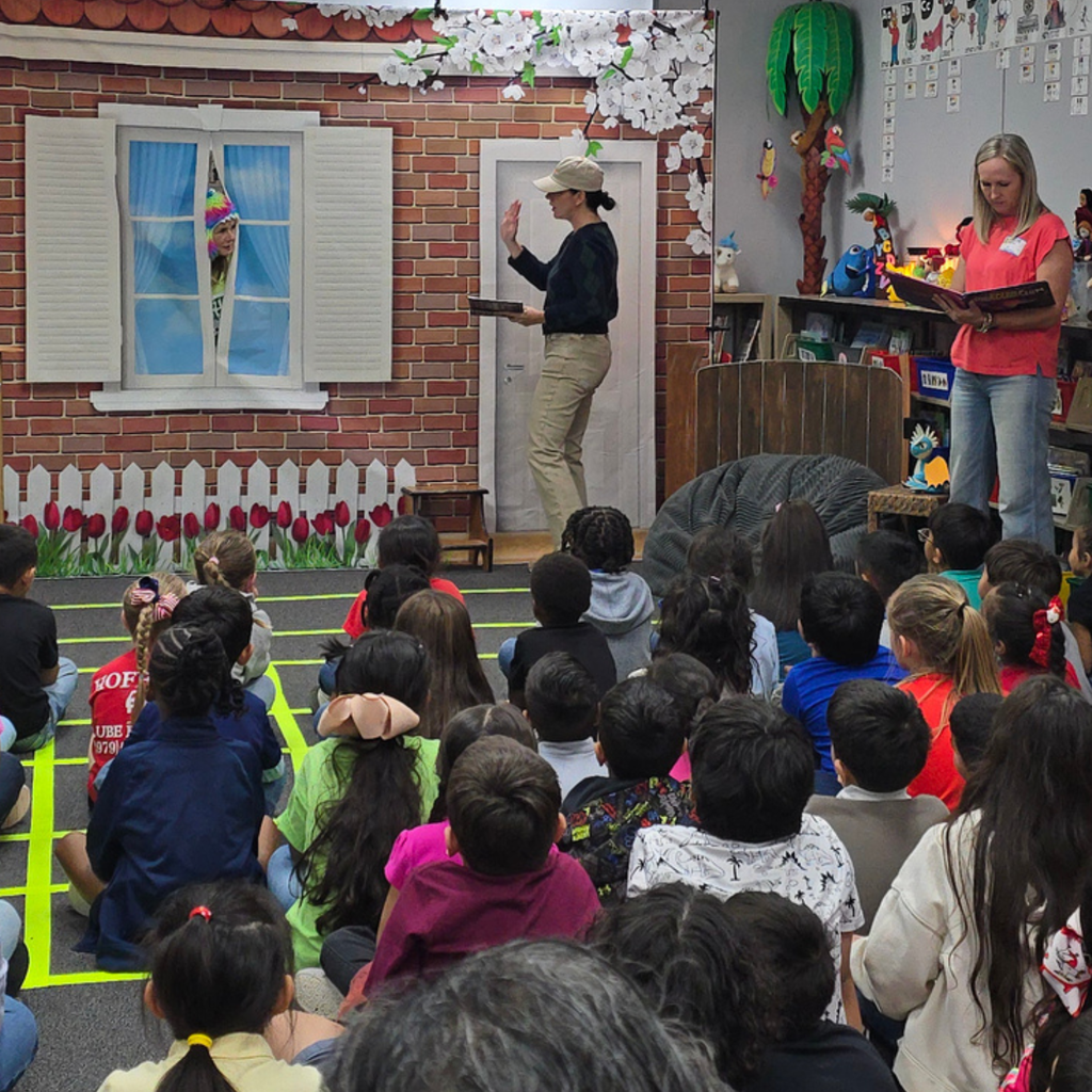 Members of the Sesame Club engage with Myatt students during a Reading Is Fundamental (RIF) book party in a decorated library setting.