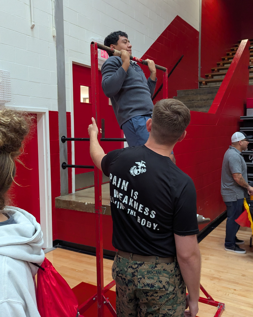 a US marine encouraging a student doing pull ups