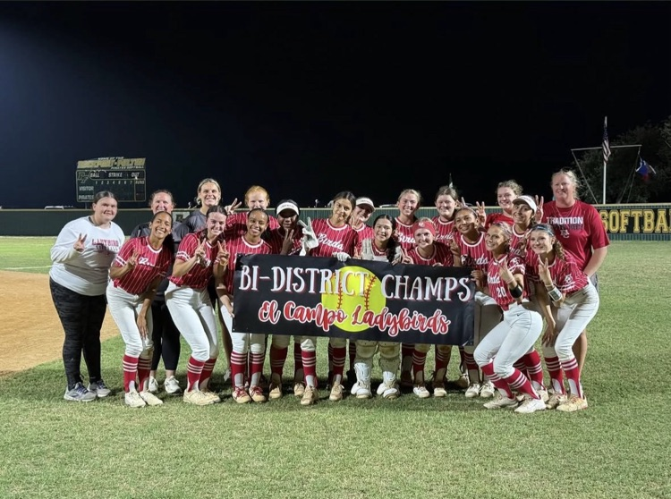 team on the field, holding a banner that says by district champions