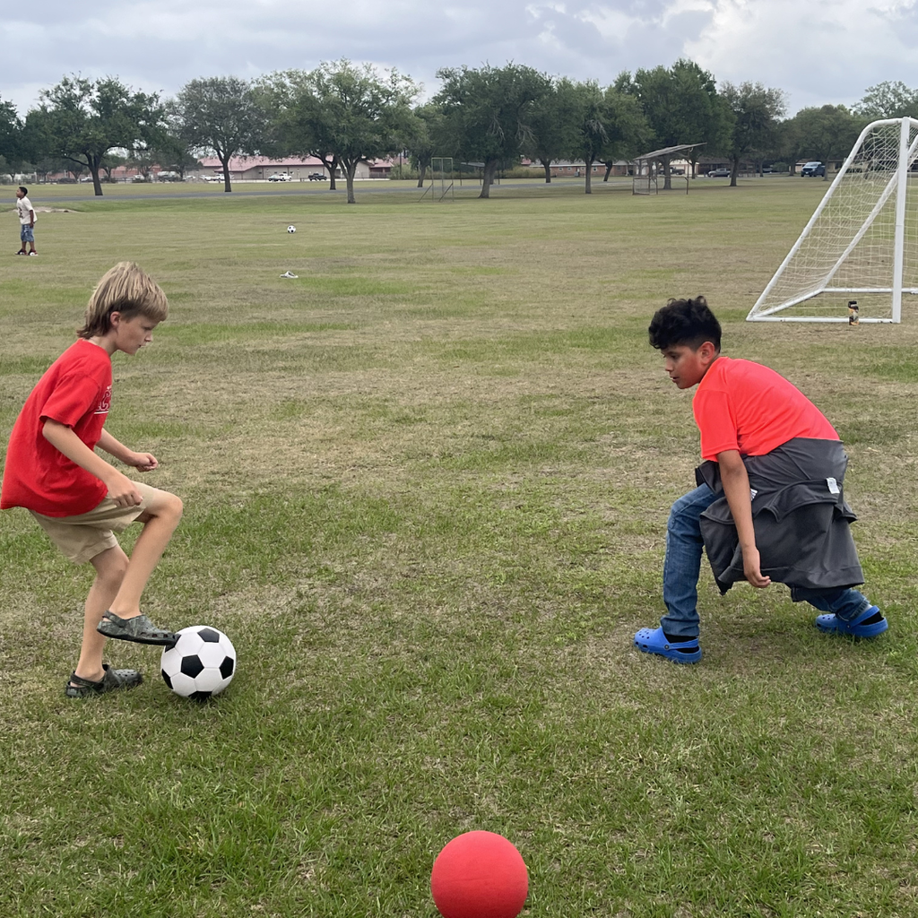 Students running and playing soccer on a grassy field during the school incentive afternoon.
