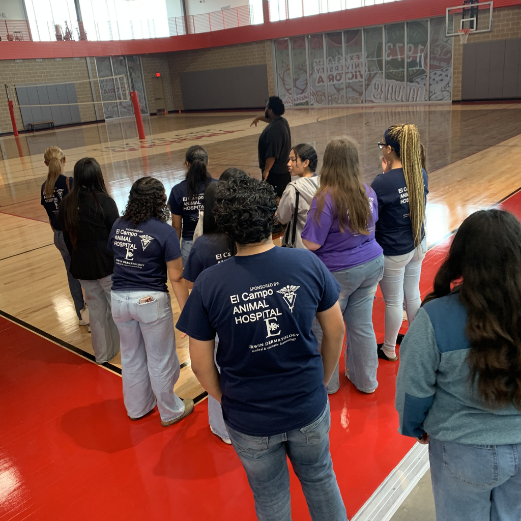group listening to a man talk in the gym with wooden floors