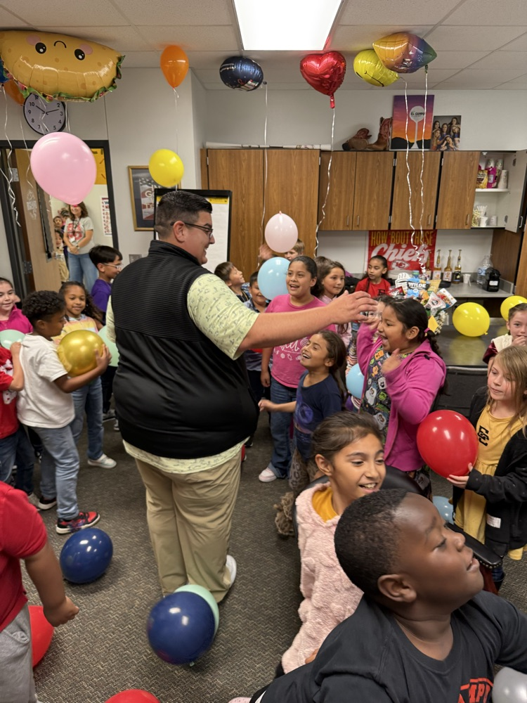 Burton surrounded by small children and colorful balloons 