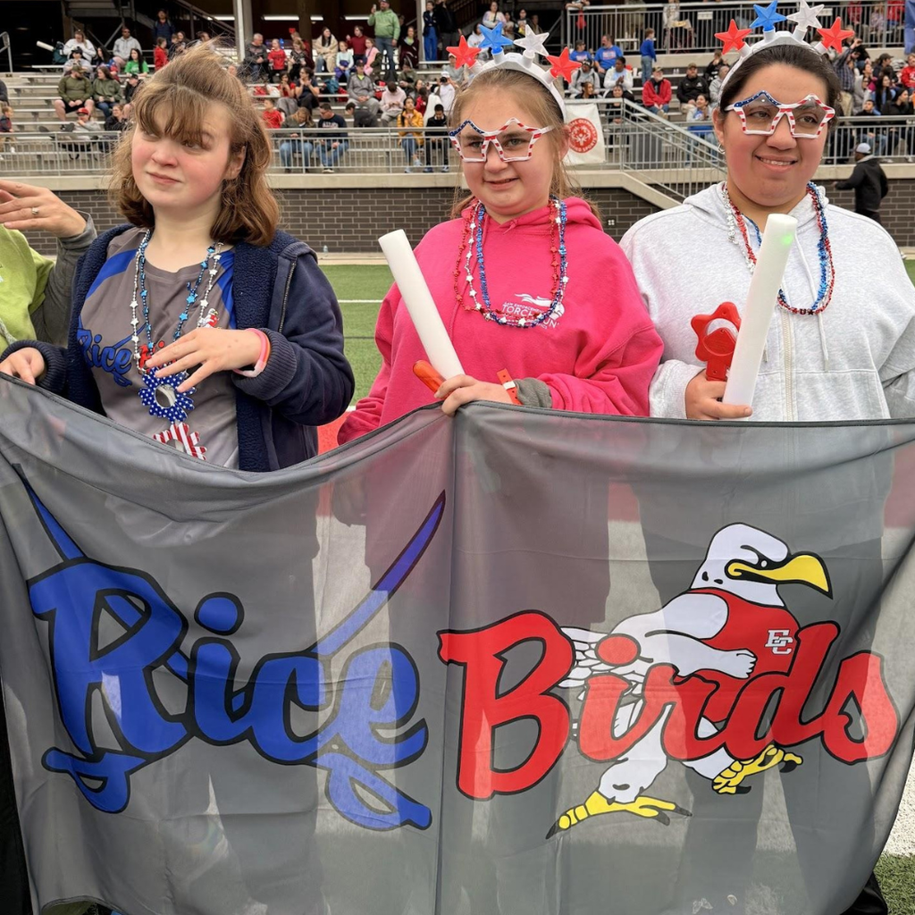 3 girls holding up the "Rice Birds" banner