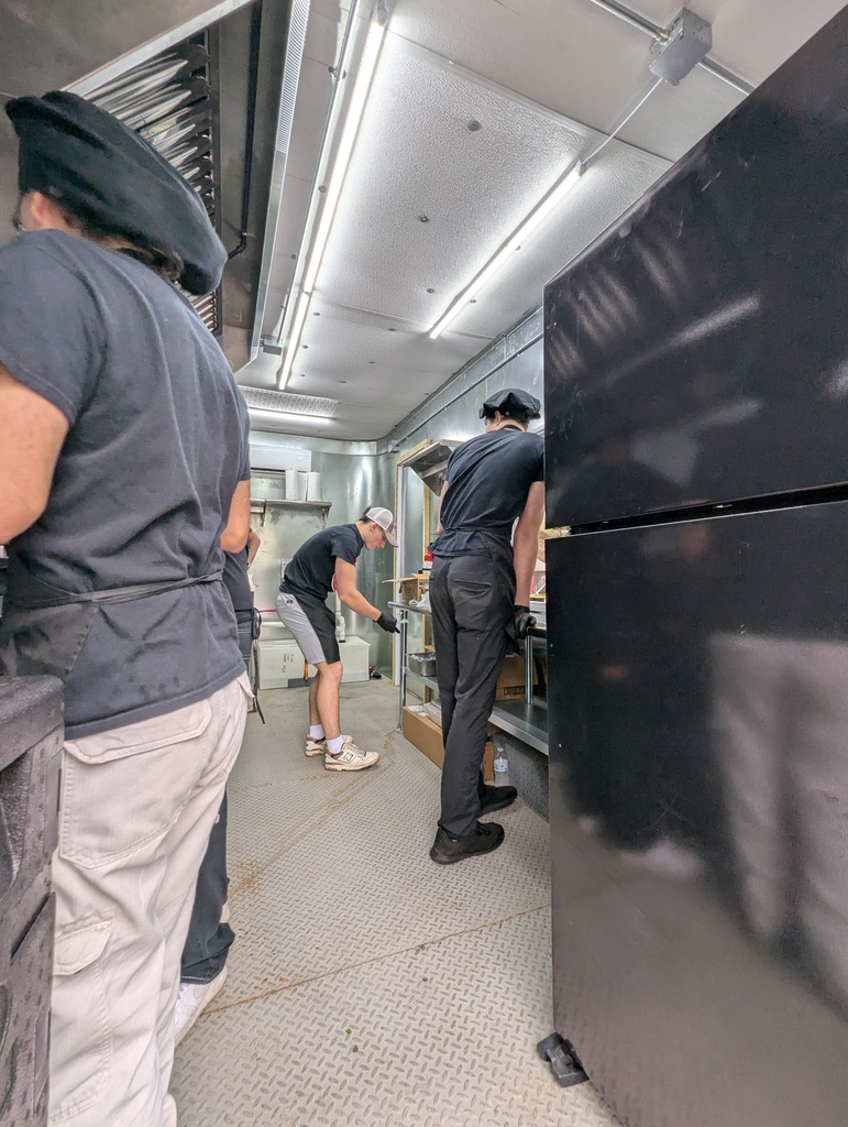 Culinary arts students working inside the kitchen of "The Bird Feeder" food truck, preparing meals for faculty and staff.