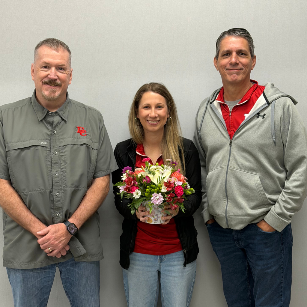 two administrators presenting Ott with a flower arrangement