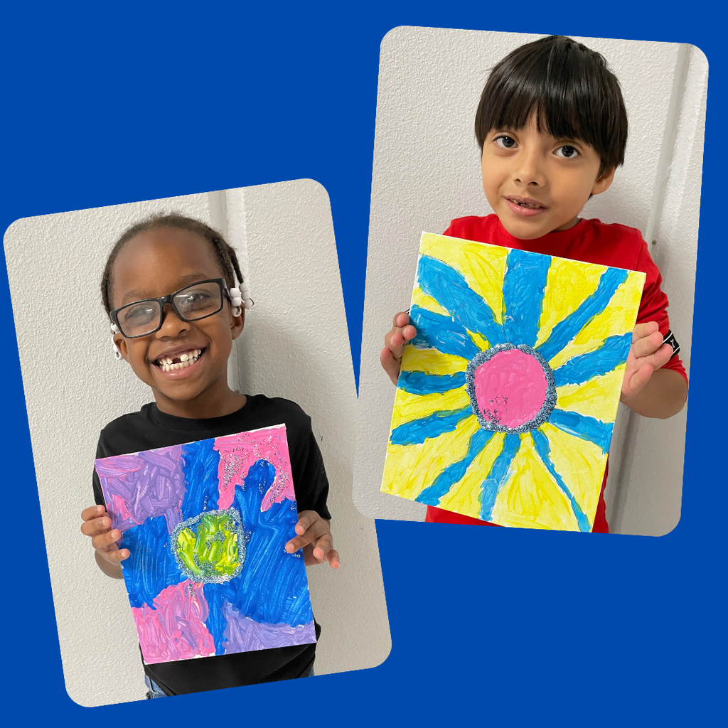 kindergarten students stand together smiling and holding up their colorful, hand-painted flower artwork. The students are each proudly displaying a unique bluebonnet-inspired painting featuring vibrant petals and bright backgrounds.
