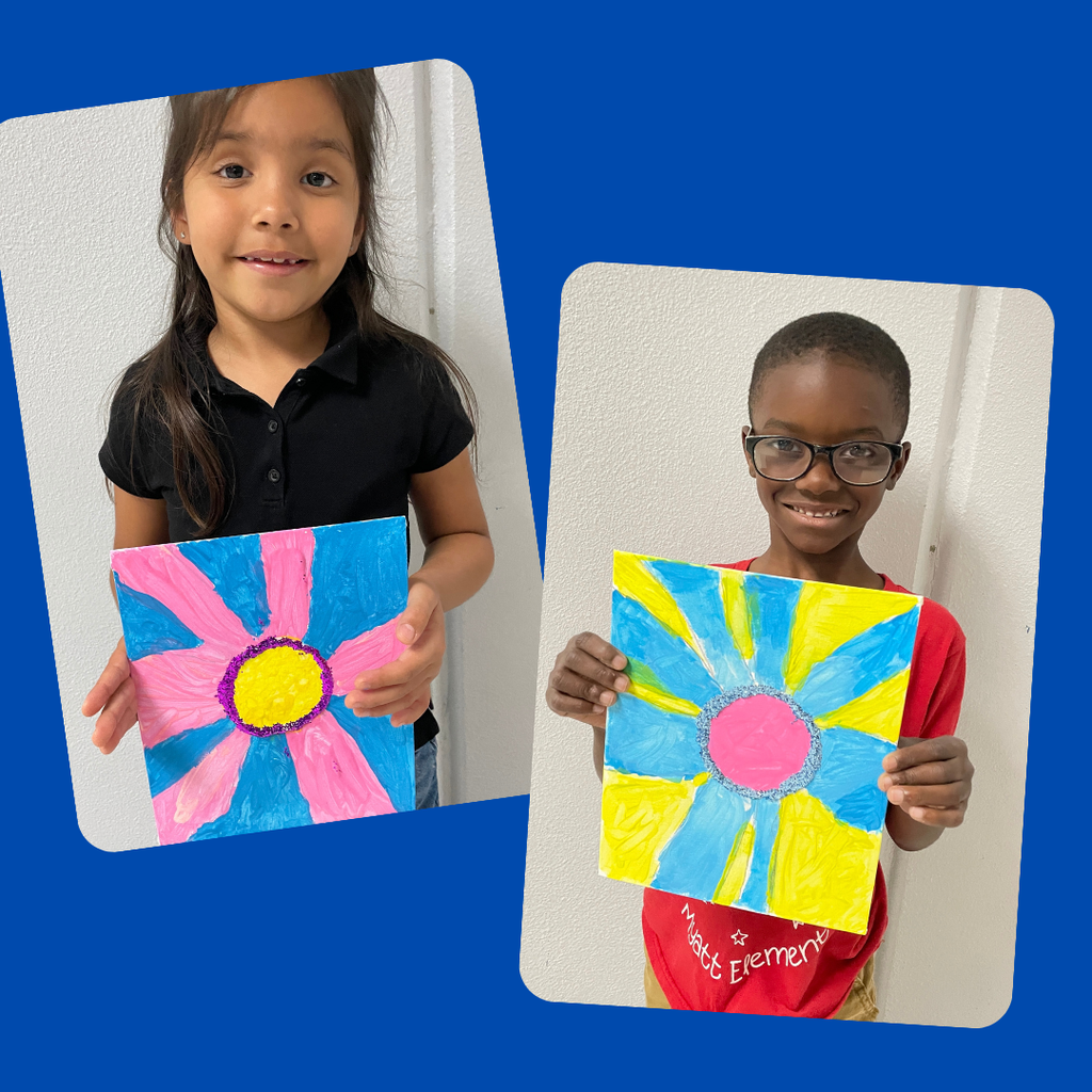 kindergarten students stand together smiling and holding up their colorful, hand-painted flower artwork. The students are each proudly displaying a unique bluebonnet-inspired painting featuring vibrant petals and bright backgrounds.