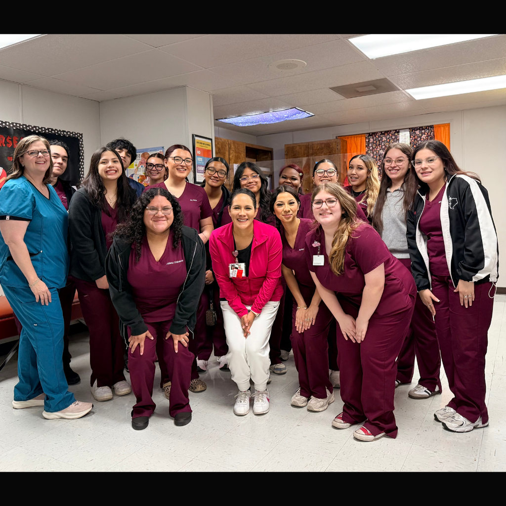 A group of about 15 El Campo High School clinical students and their instructor posing in a classroom. The students are wearing maroon scrubs and the instructor is in blue, all smiling for a celebratory final day photo.