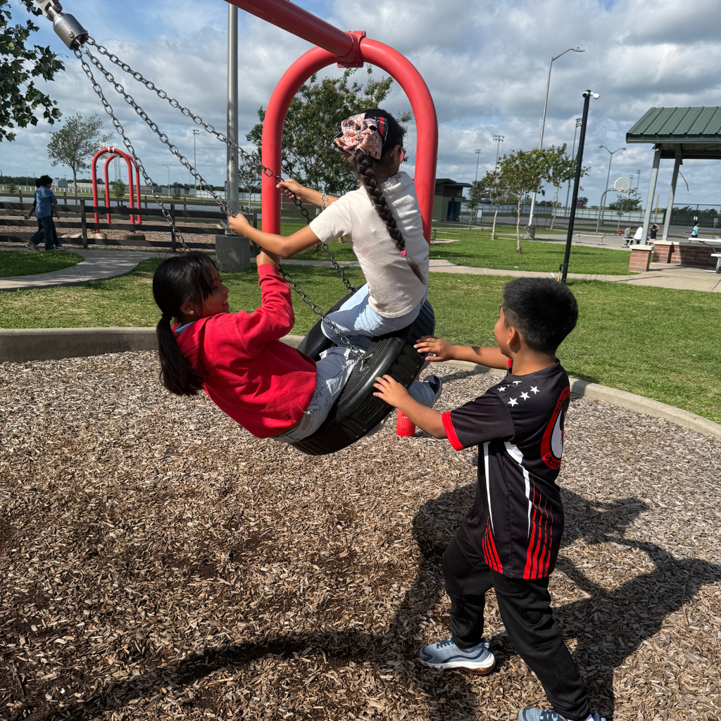 3 kids on the tire swing at the park