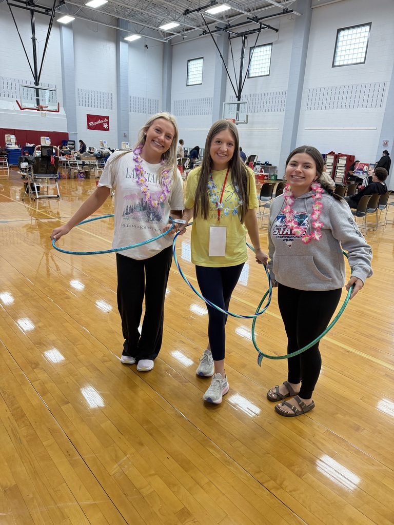 3 students at the blood drive wearing leis holding hula hoops