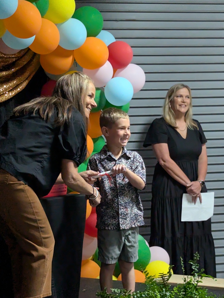 teacher handing a small boy his kindergarten diploma