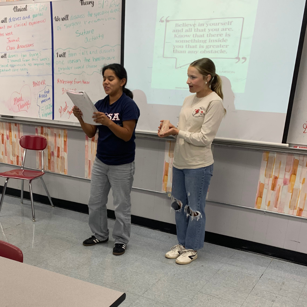 2 girls presenting their wound at the front of the class