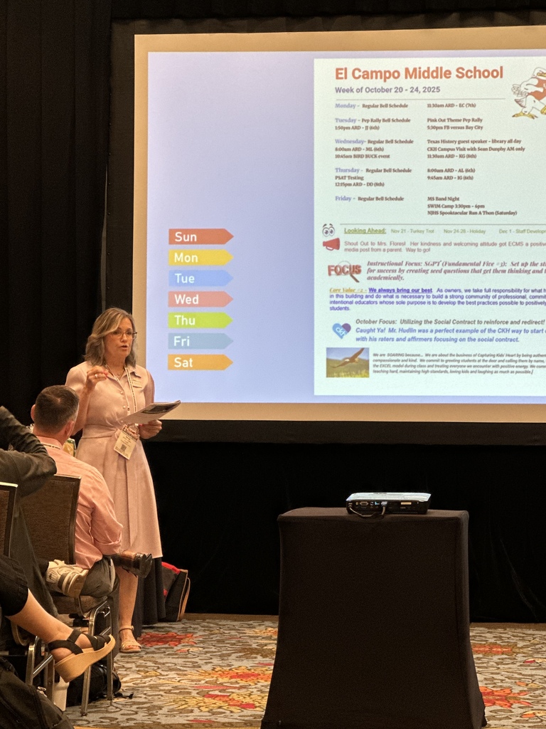 principal fellers presenting to a room full of adults with a slide of information displayed behind her