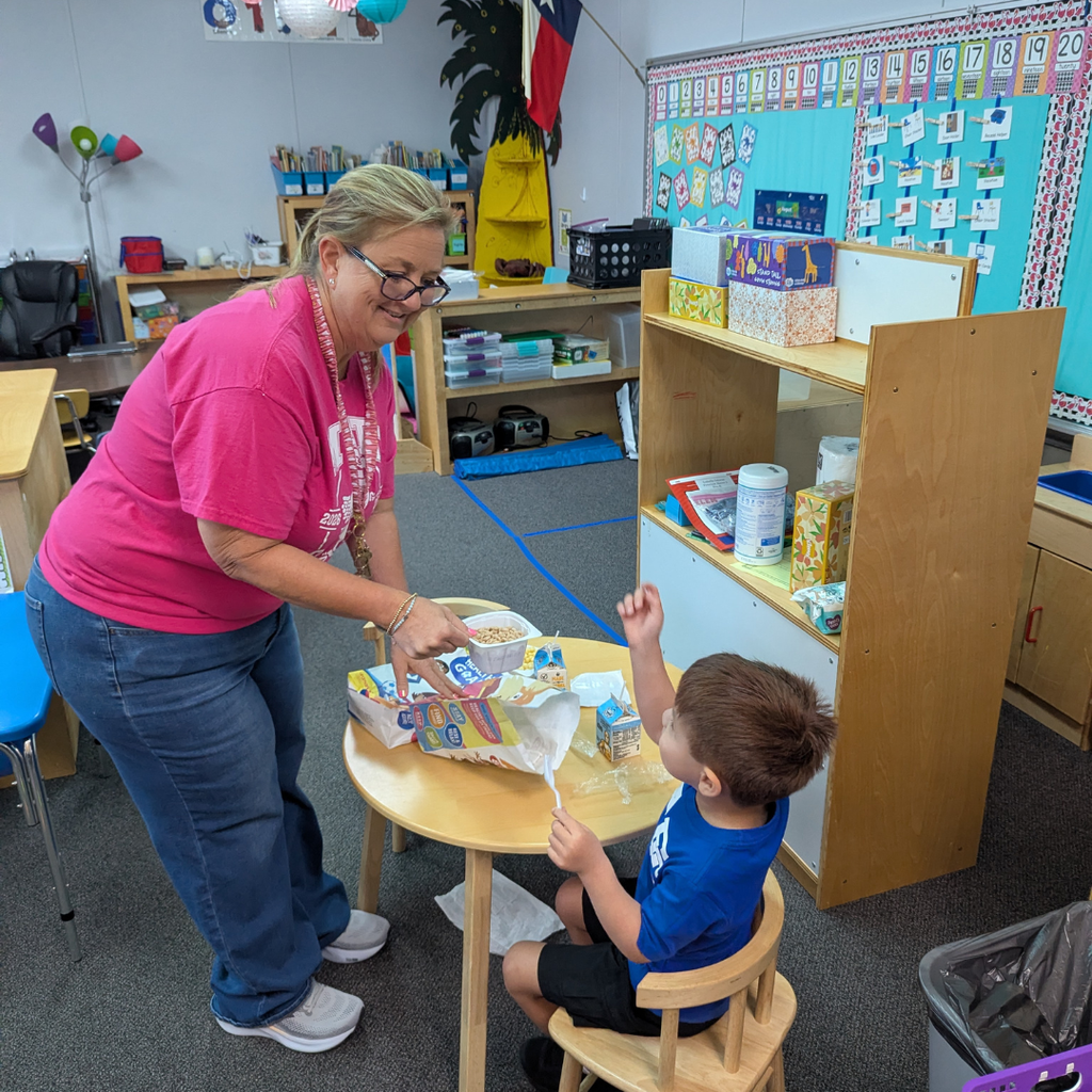 teacher helping small child with breakfast