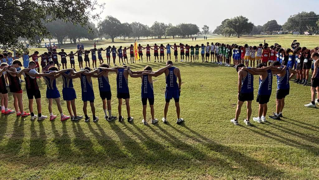 several athletes gathered in a large circle arms connected praying