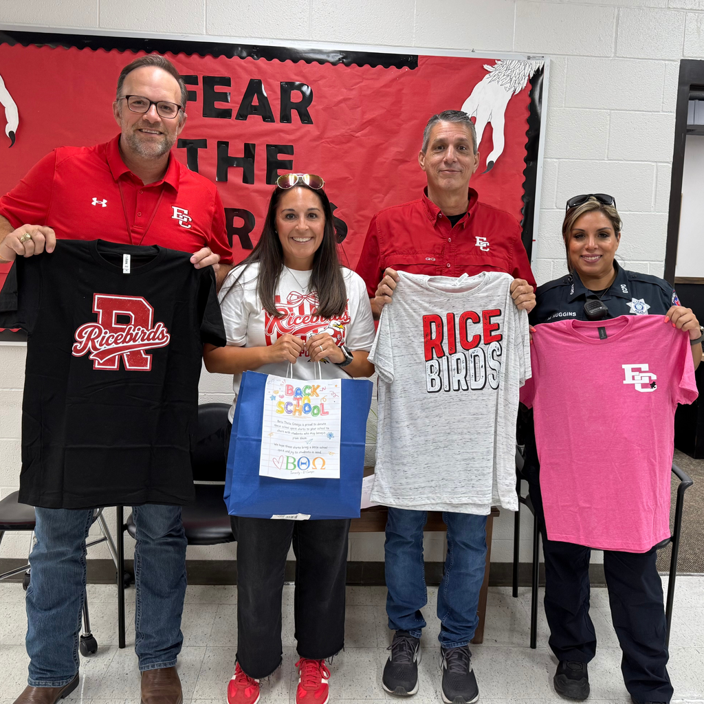 4 adults holding shirts at high school