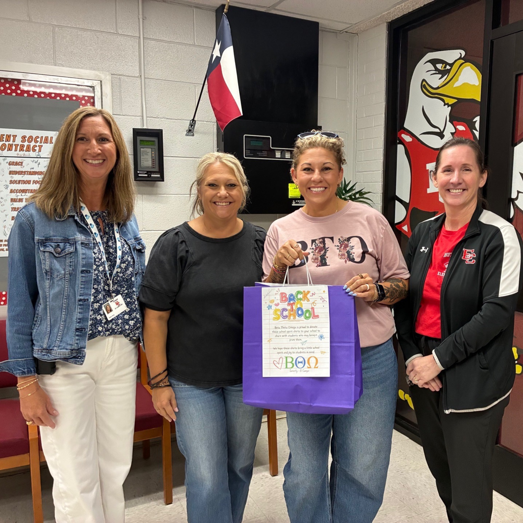 2 adults at hutchins accepting a bag of shirts from 2 ladies