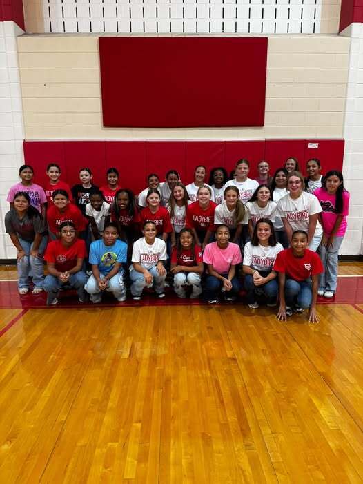 volleyball girls posed for a group picture in the gym