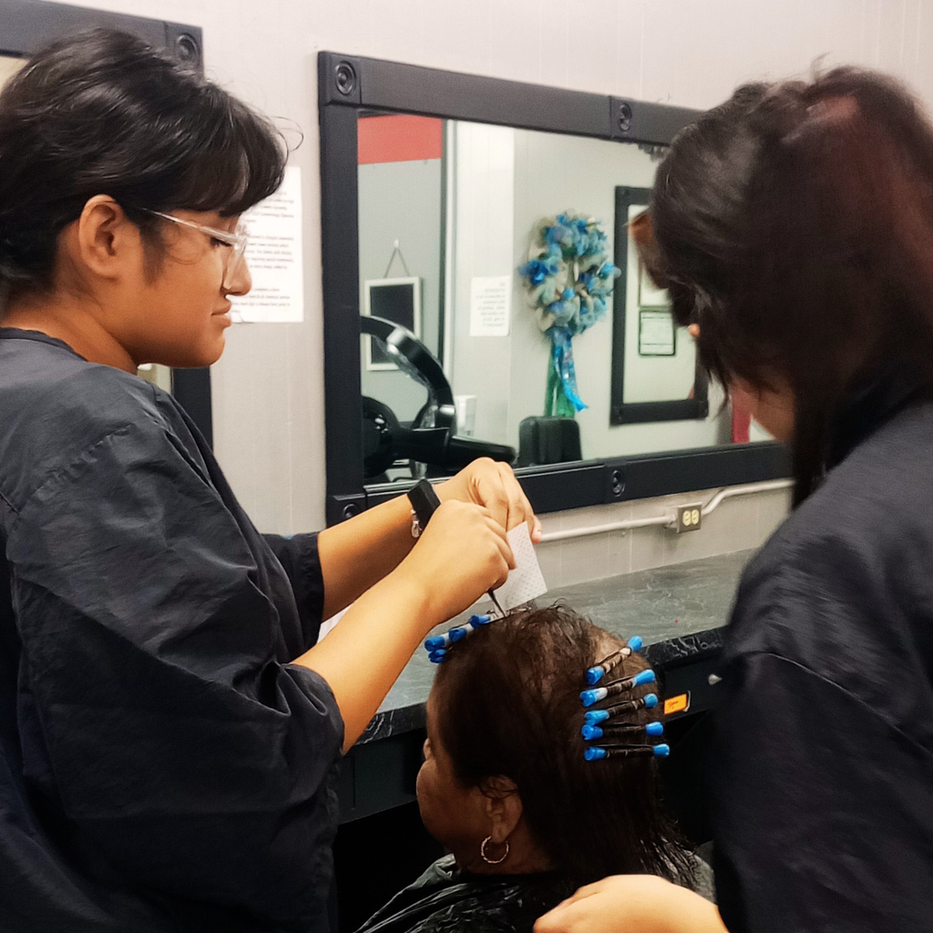 Two girls work to perm a ladies hair.