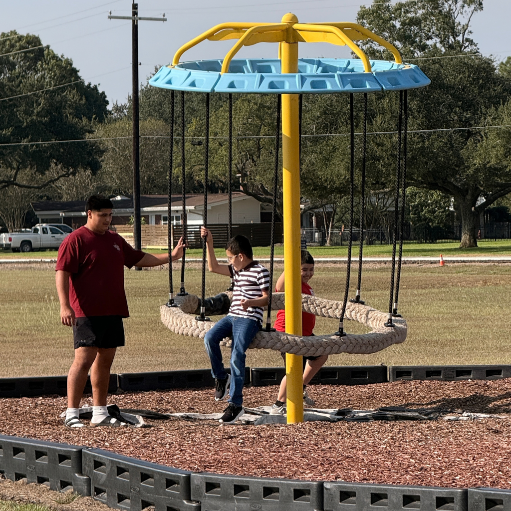 high school boy helping small children on the playground