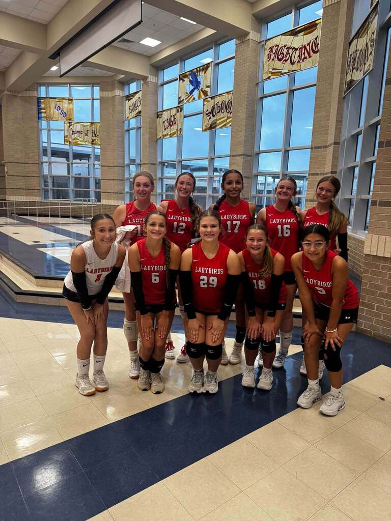 Members of the El Campo Middle School Ladybirds volleyball team 1 posing together in uniform indoors.