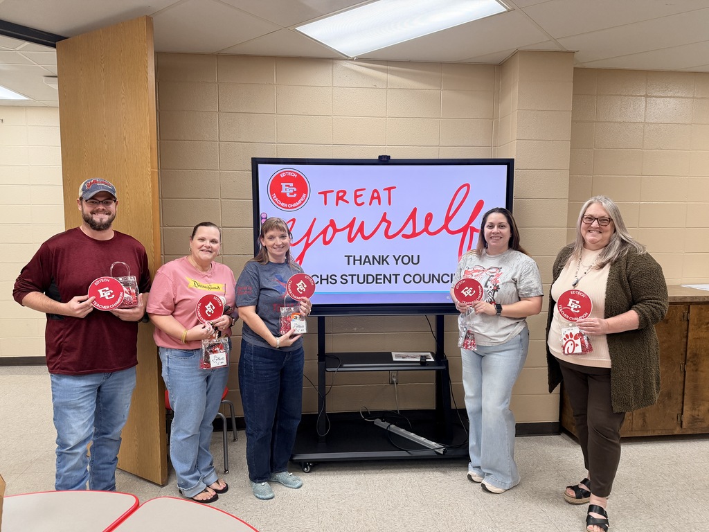 Five school staff members stand together holding thank-you gifts and gift bags in front of a digital screen that reads "Treat Yourself - Thank You ECHS Student Council."