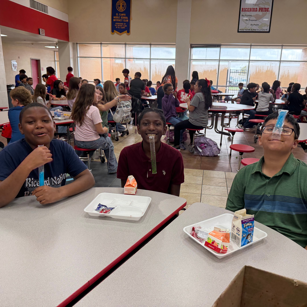 Three ECMS middle school students sitting at cafeteria tables during lunch enjoying popsicles.