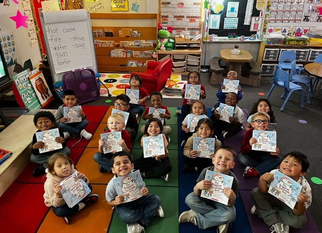 small children sitting on rug showing off their book