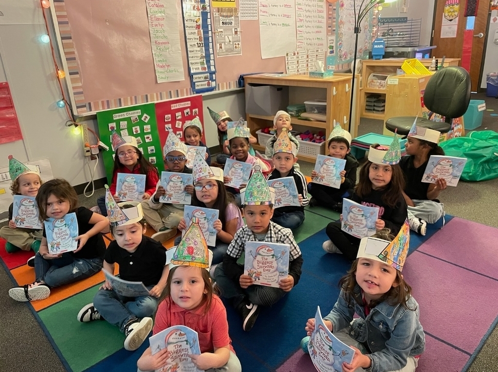 small children sitting on rug showing off their book