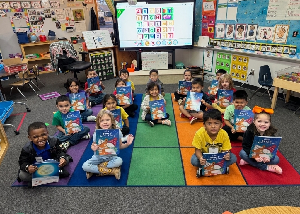 small children sitting on rug showing off their book