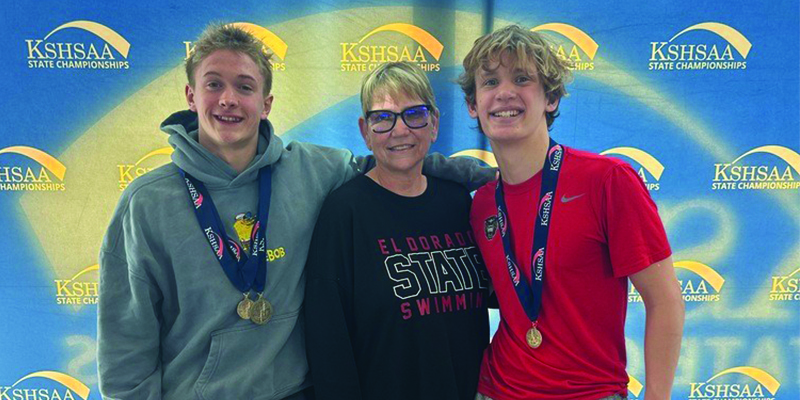 Sam, Brody and Coach Solorio pose with their medals in front of the KSHSAA state championships background