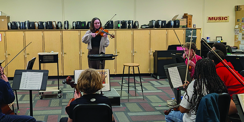 Student Teacher Katelyn Valdez demonstrates a note on her violin for the students