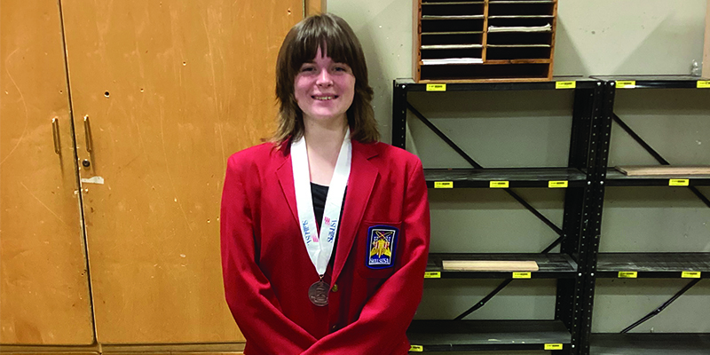 Student smiles while wearing a bronze medal