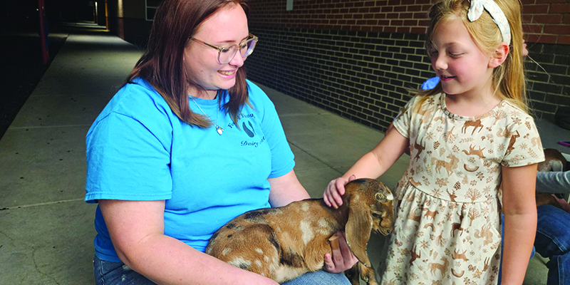 Skelly student petting a young goat