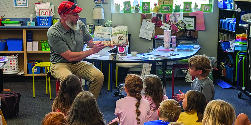 Rotary member Isaac McNary reads a book to kindergarten students