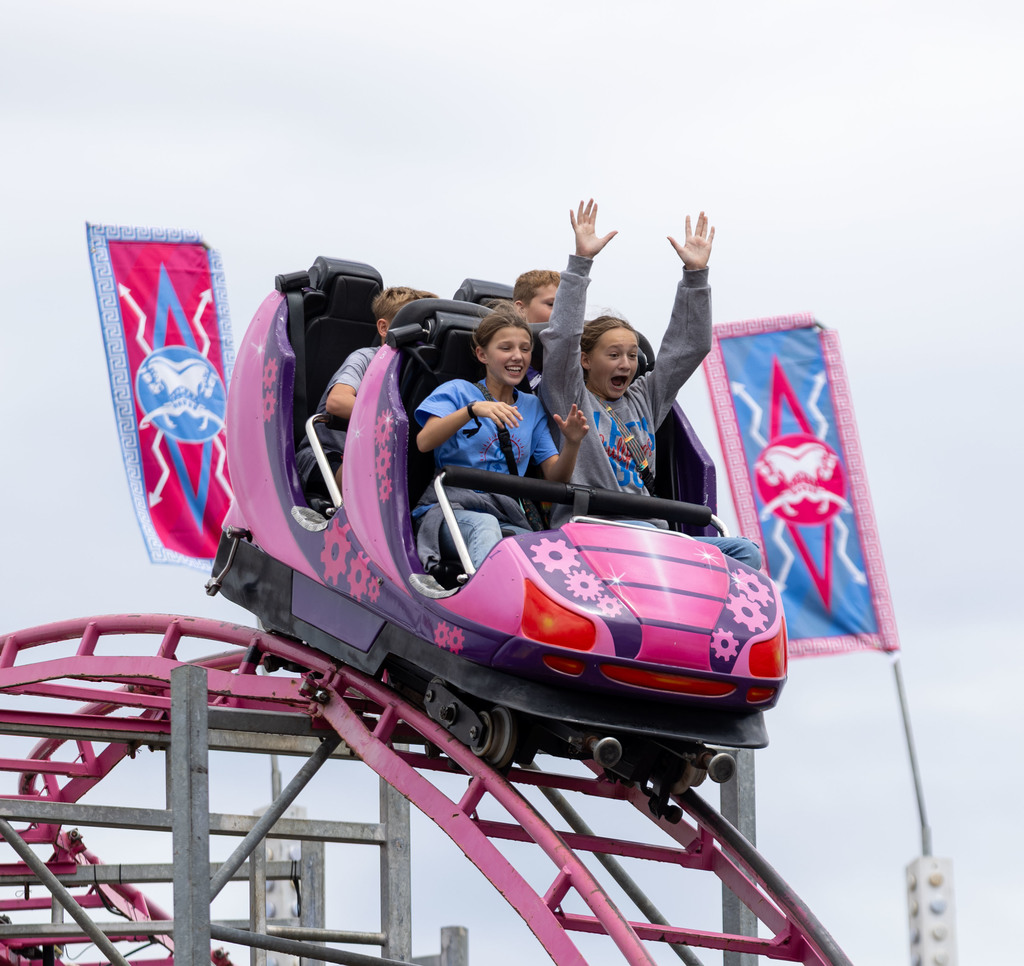Two girls in the front seat of a pink roller coaster