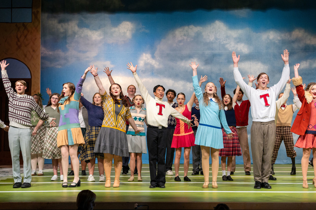 A group of performers in 1920s costumes on stage for their school musical