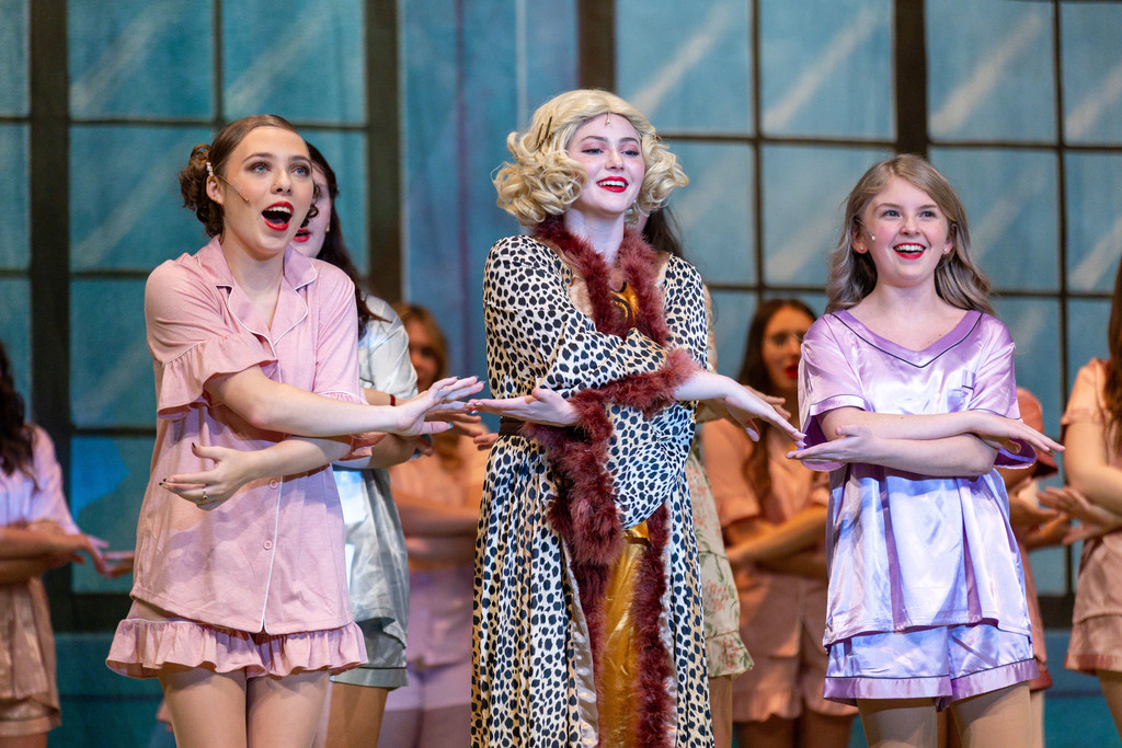 Three teenage girls in pajama costumes on the set of their school musical