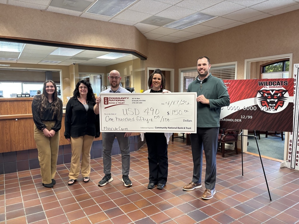 CNB&T employees stand with USD 490 Superintendent Jenifer Davis, holding an oversize check for $150 with the EHS mascot debit card poster in the bank lobby