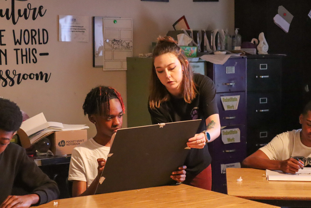 JUNIOR HIGH ART TEACHER HELPING STUDENT WITH LIVE FIGURE DRAWING