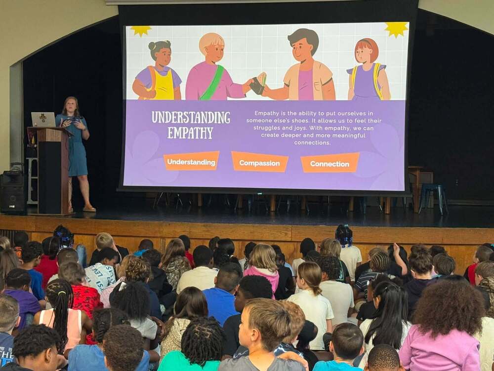 counselor standing on a stage in front of students talking about understanding empathy