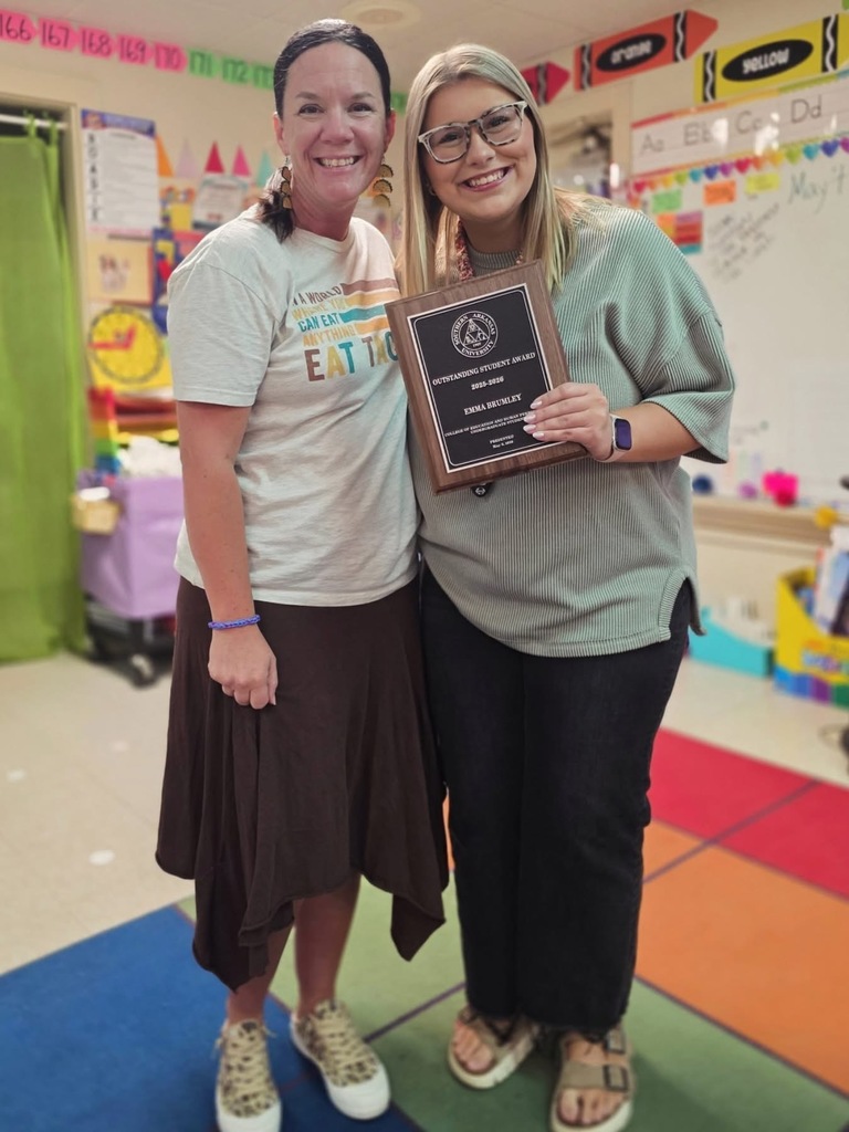 Emma Brumley smiles while holding an Outstanding Student Award plaque from Southern Arkansas University’s College of Education and Human Performance. She is pictured indoors in a classroom setting with a softly blurred background.