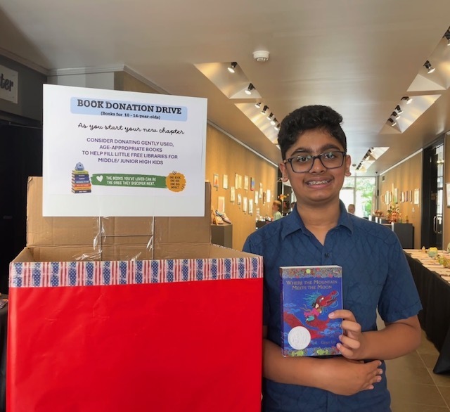 ESD student pictured holding a book next to book donation drive box