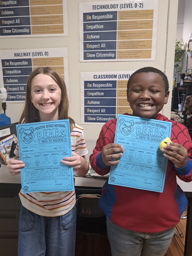 two students standing with a positive office referral
